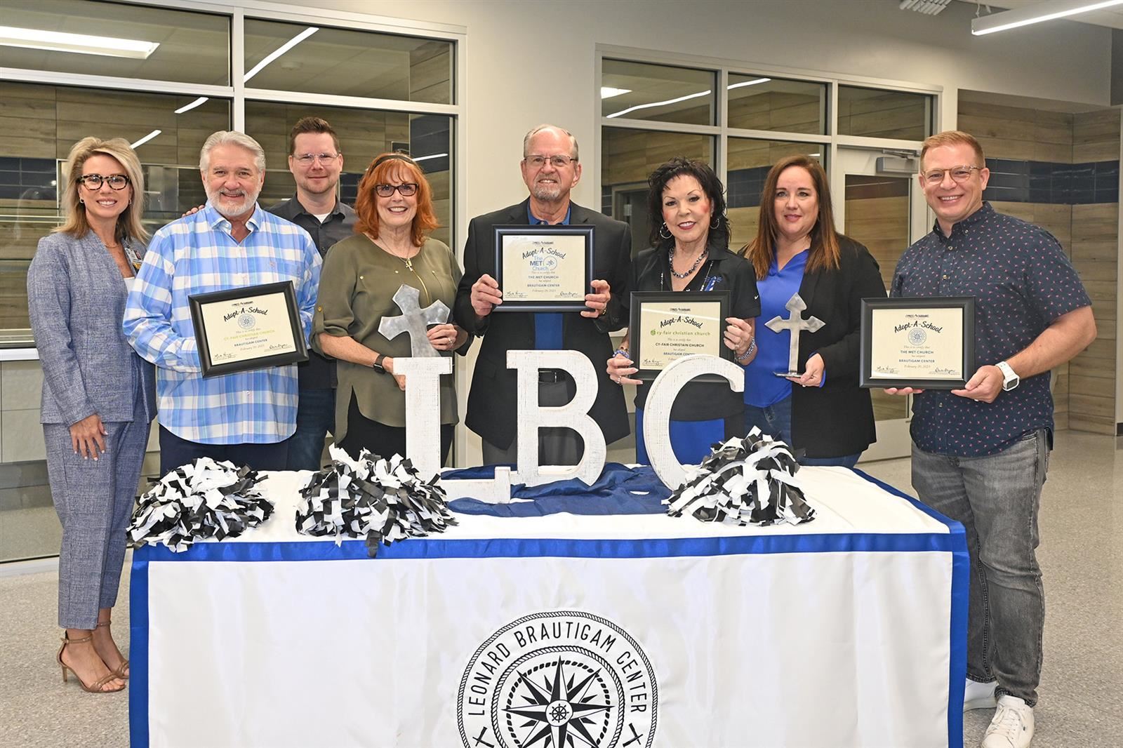 Brautigam Center Principal Martha Strother, third from right, and campus namesake Leonard Brautigam hold certificates.